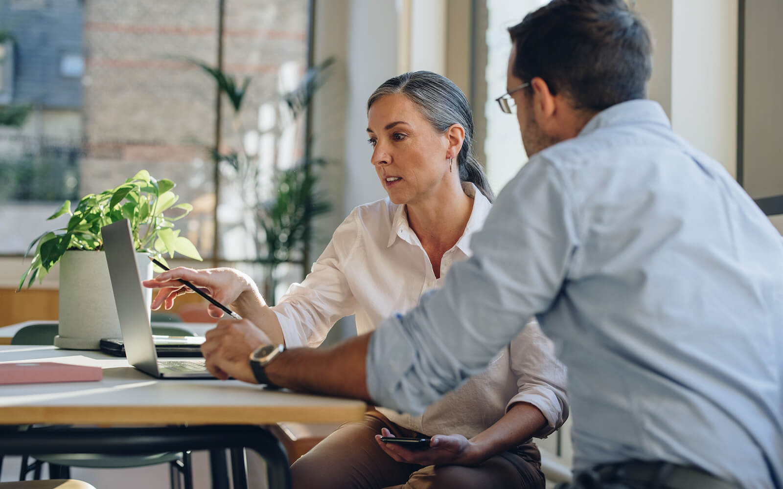 Woman and man reviewing documents digitally while sitting at a table
